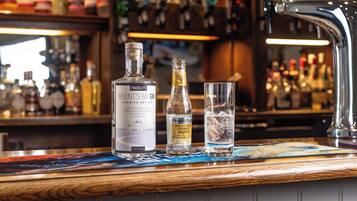 A bar counter with bottles of Pengeley's Mount's Bay Gin and Fever Tree Premium Iced Tonic Water, and a glass of water.