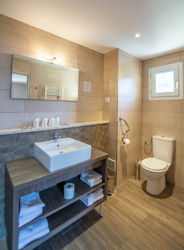 A modern bathroom with a large sink, mirror, towel rack, and toilet.