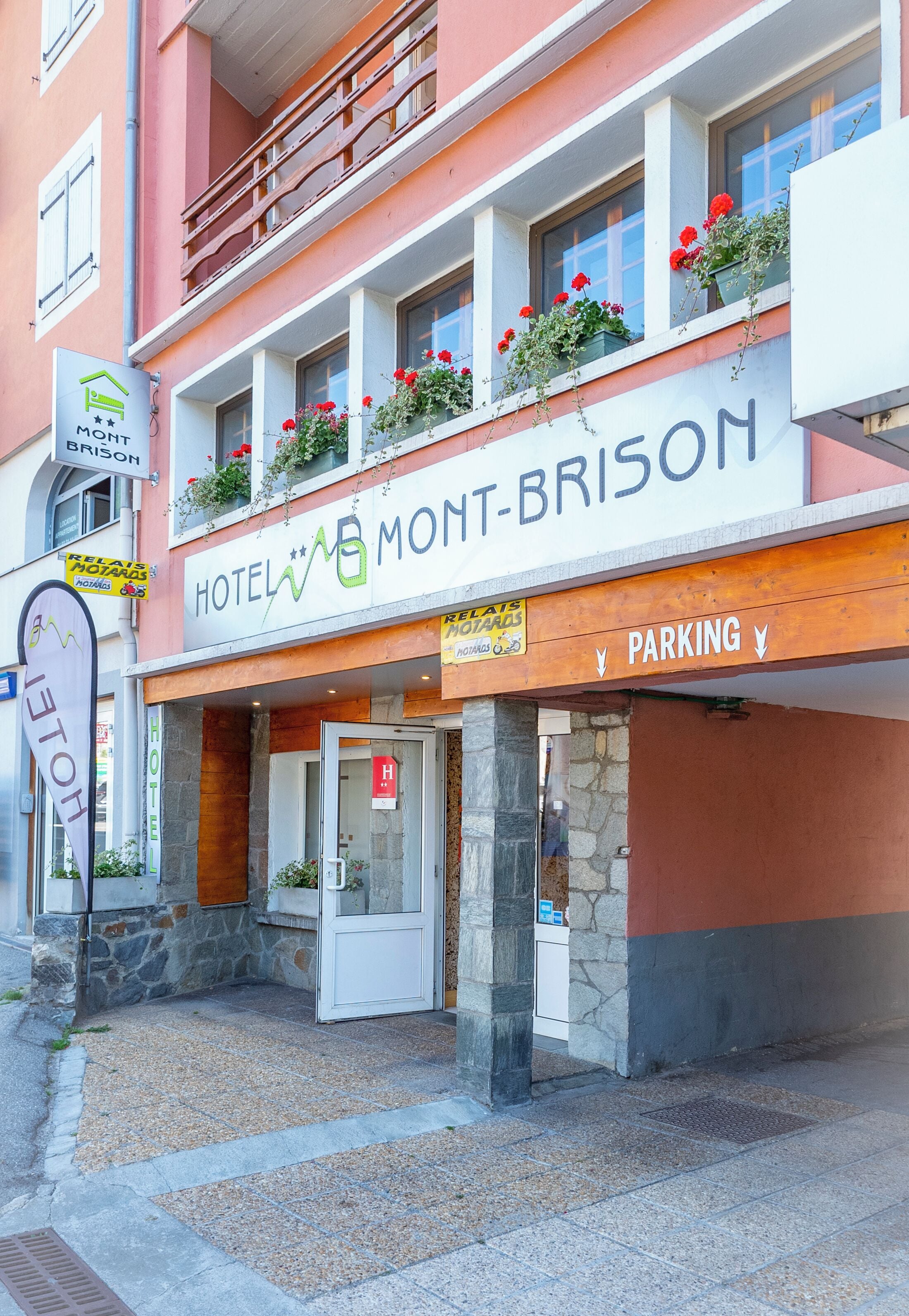 A hotel named "HOTEL MONT-BRISON" with a sign indicating parking.