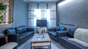 A modern living room with a sofa set, a coffee table, and a TV. - Hôtel Mont-Brison (Briançon)