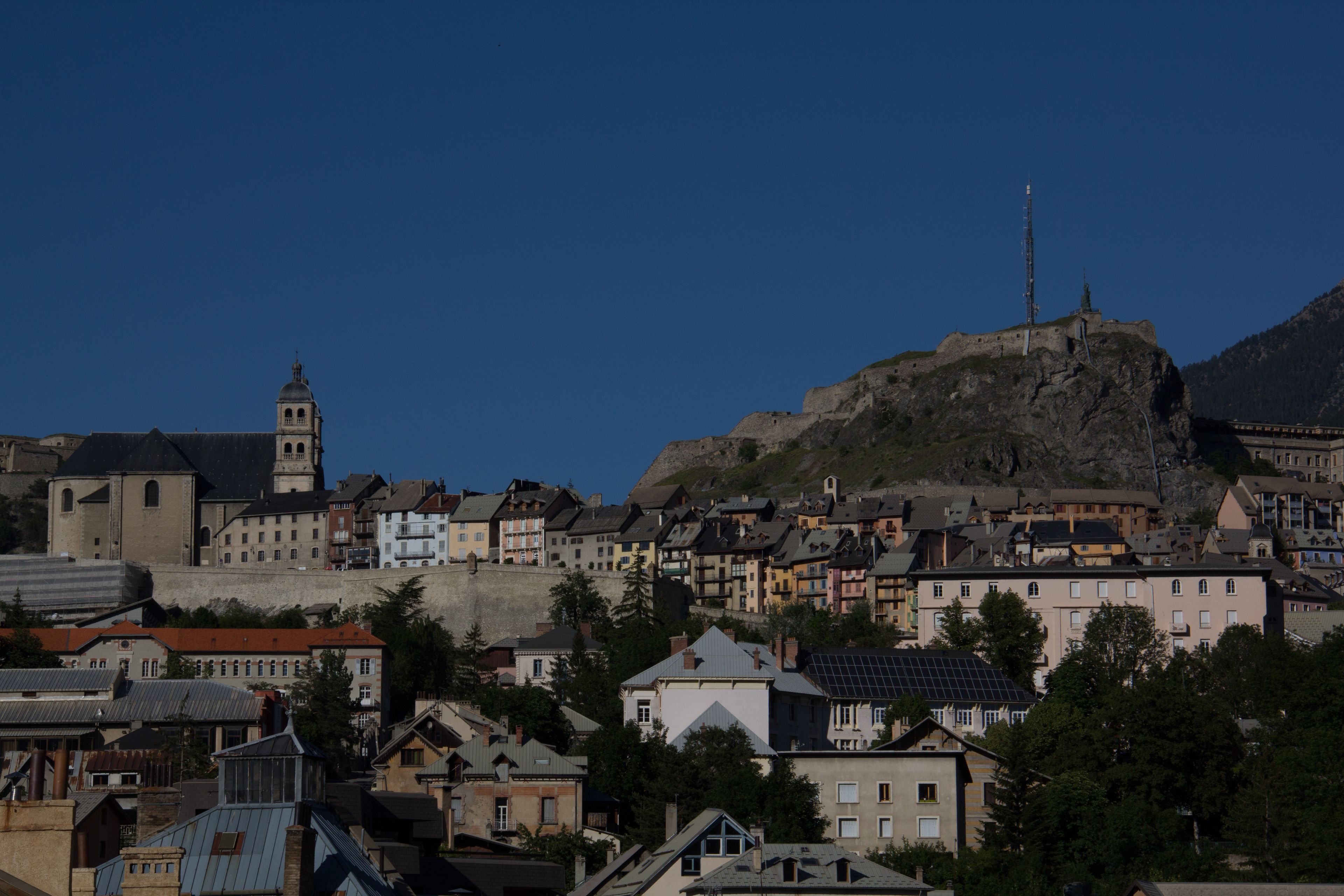 A town with a prominent church tower and a hilltop structure.