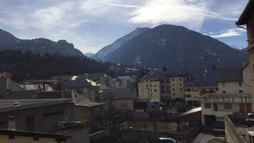 Un quartier résidentiel avec des immeubles, une voiture et des montagnes en arrière-plan.