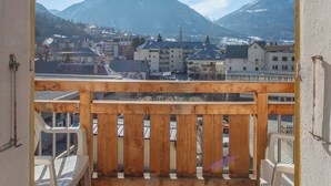 A balcony with wooden railings and a view of a town and mountains. - Hôtel Mont-Brison (Briançon)