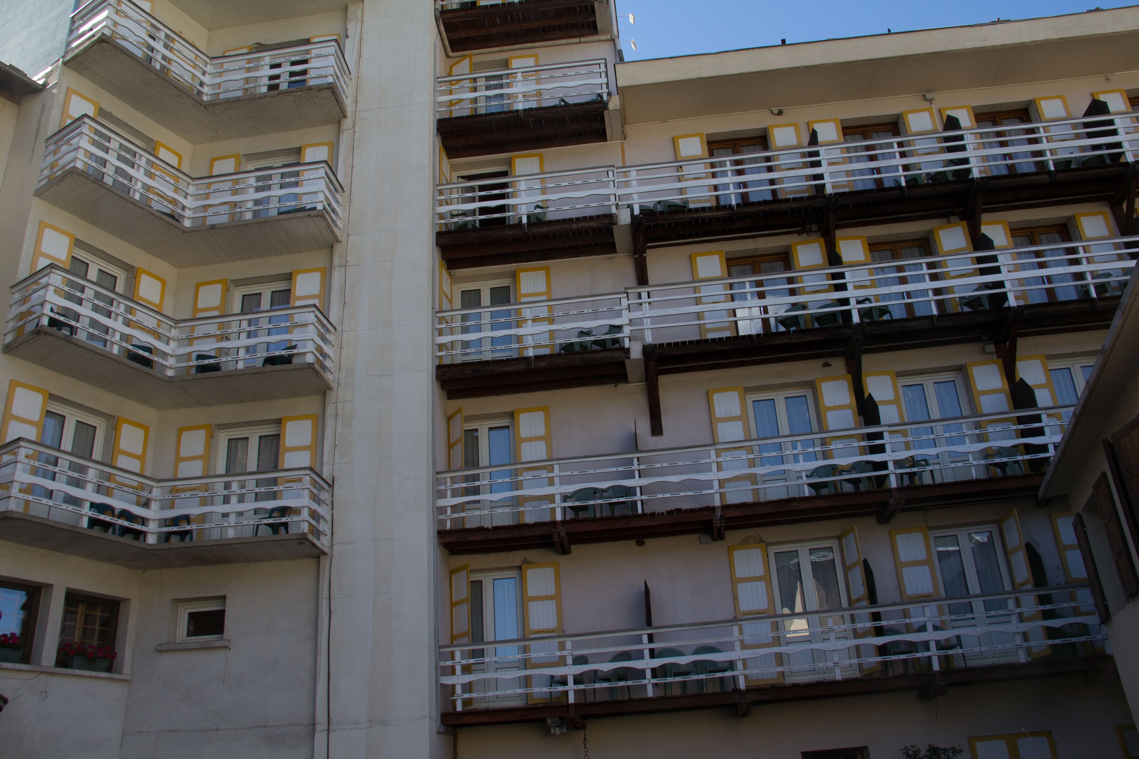Un edificio de varios pisos con balcones, ventanas con marcos amarillos y fachada color crema.