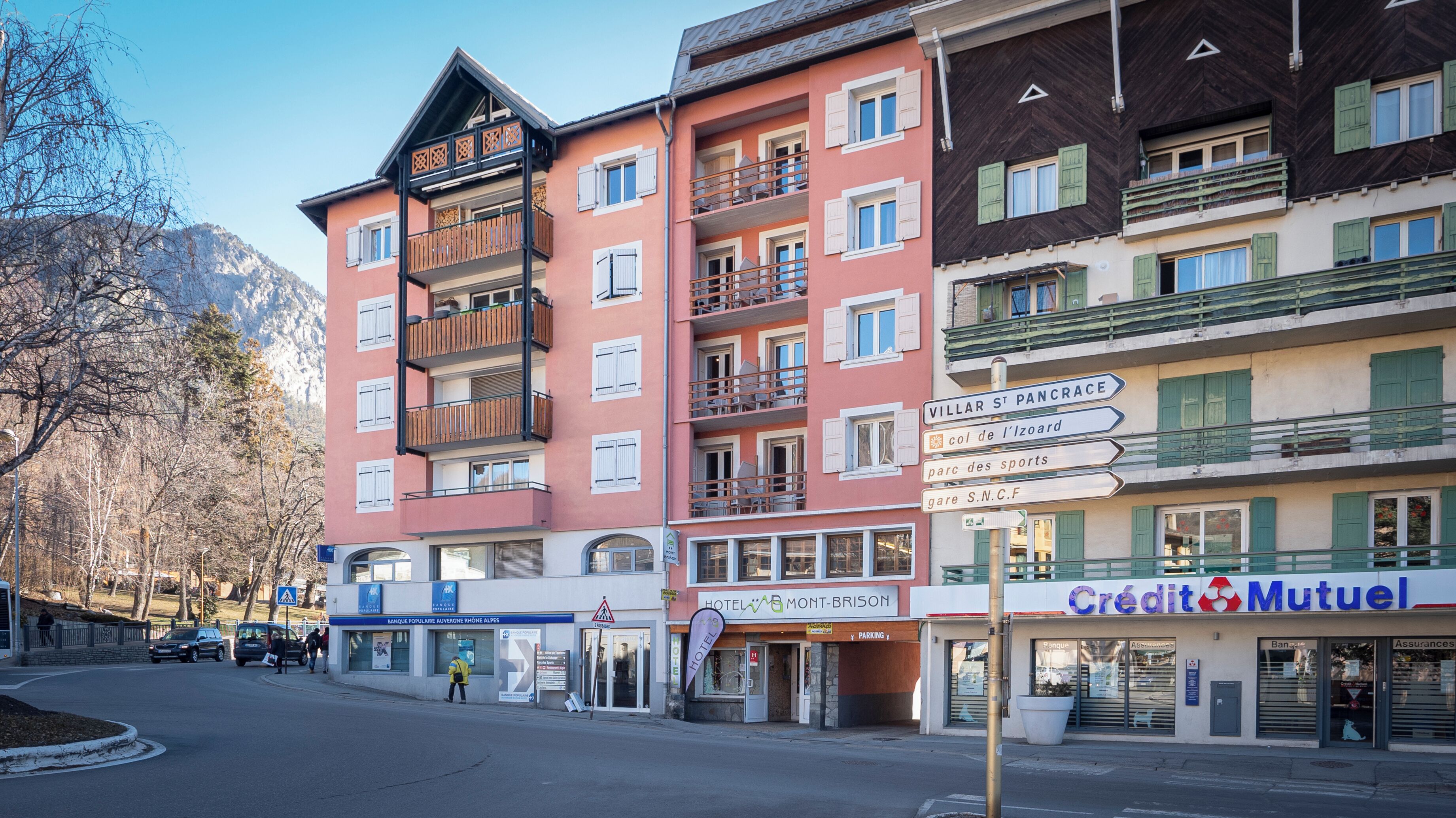 Un hotel de varios pisos con balcones, un letrero que dice 'Hotel Mont-Brison' y una sucursal de 'Credit Mutuel'.