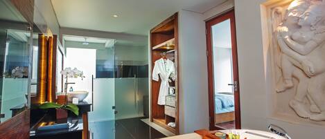 A modern bathroom with a large bathtub, a wooden vanity, a robe hanging on a rack, and a decorative wall sculpture.