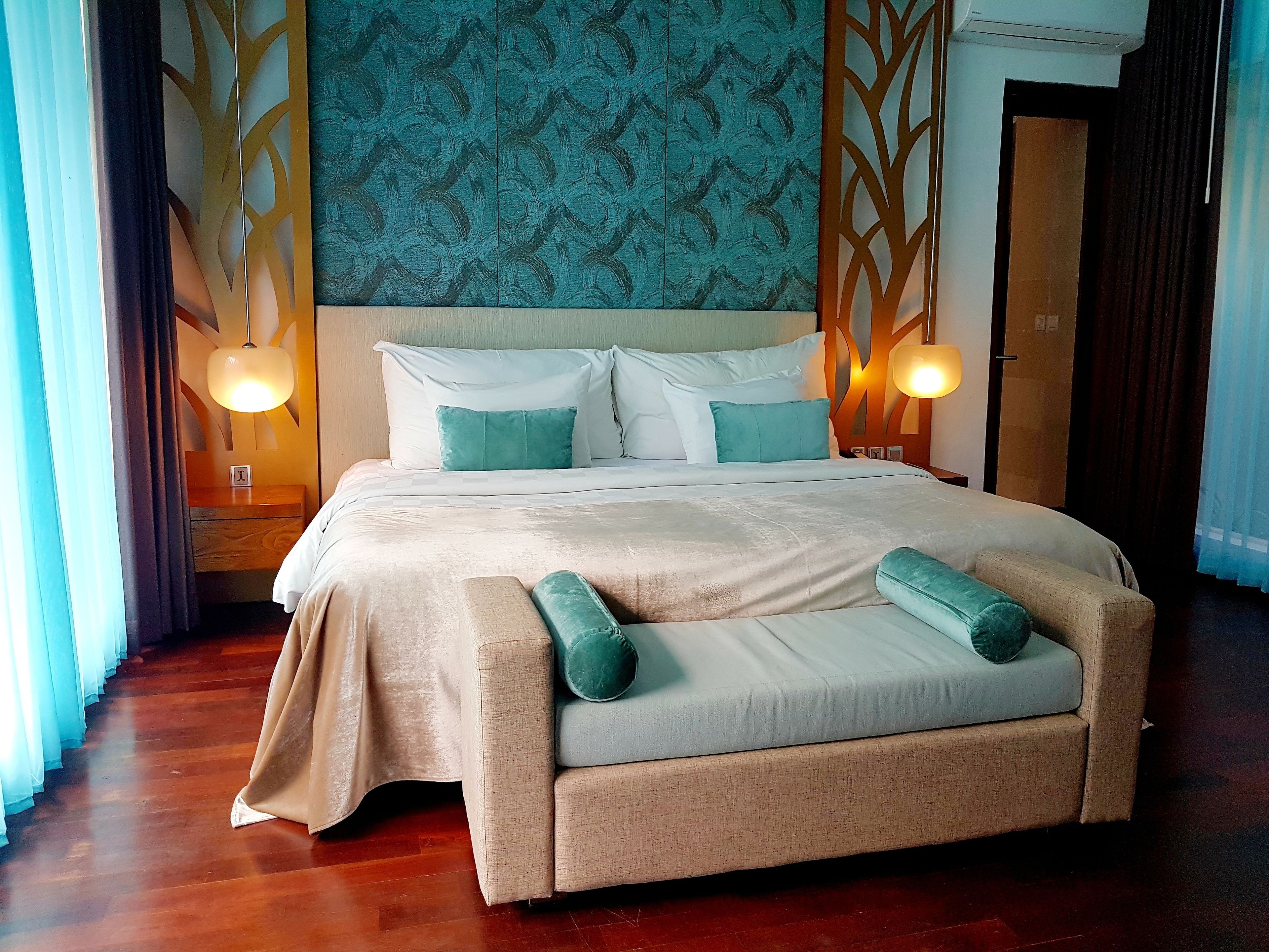 A spacious bedroom with a large bed, two bedside lamps, and a wooden floor.