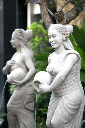 A statue of a woman holding a child and a jug, with water flowing from the jug. - The Leaf Jimbaran (Jimbaran)