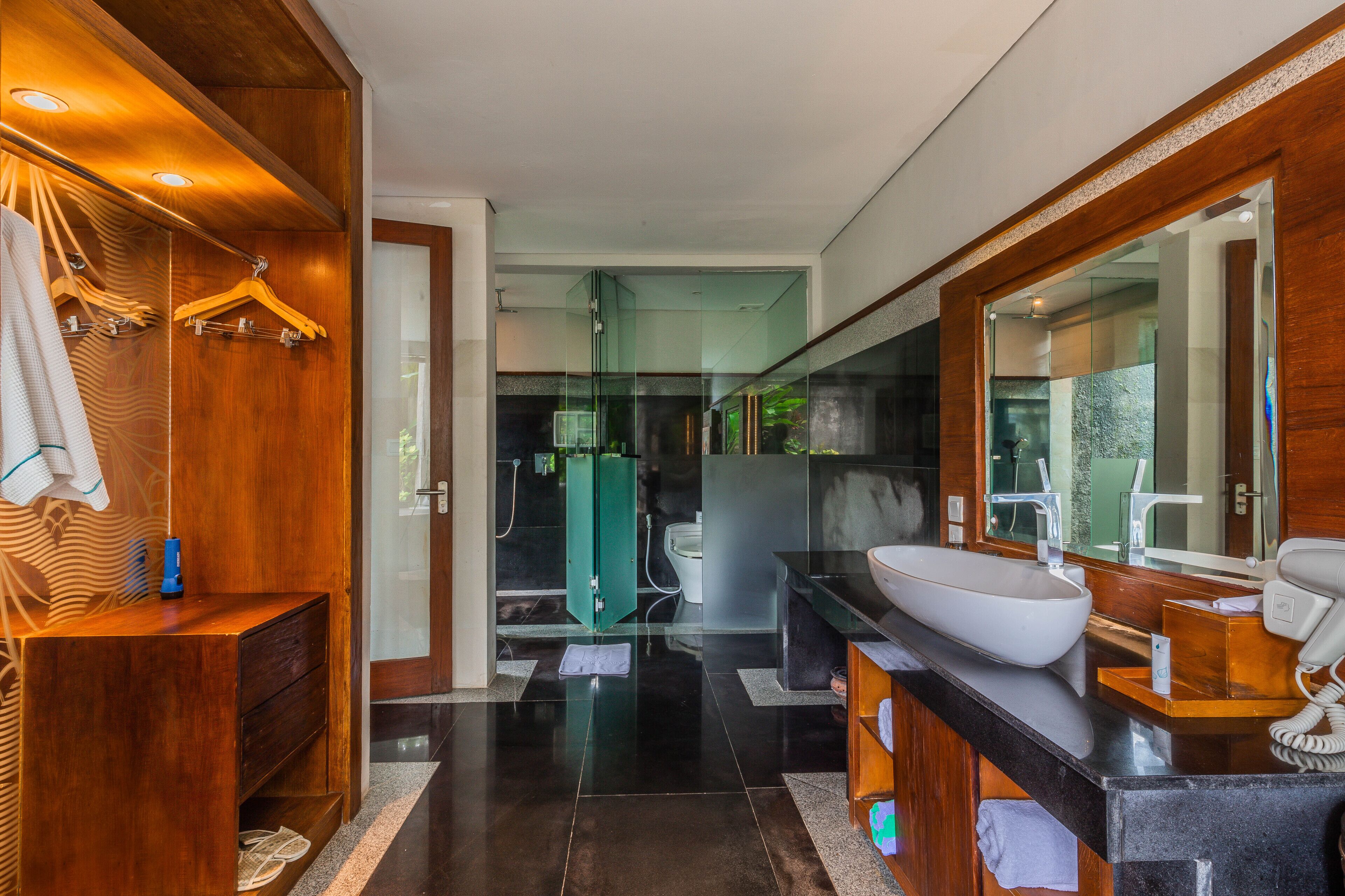 A modern bathroom with a wooden vanity, a large mirror, and a glass shower enclosure.