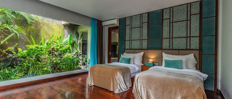 Habitación de hotel con dos camas, un ventanal con vistas a la vegetación y un cabecero de estilo tradicional.