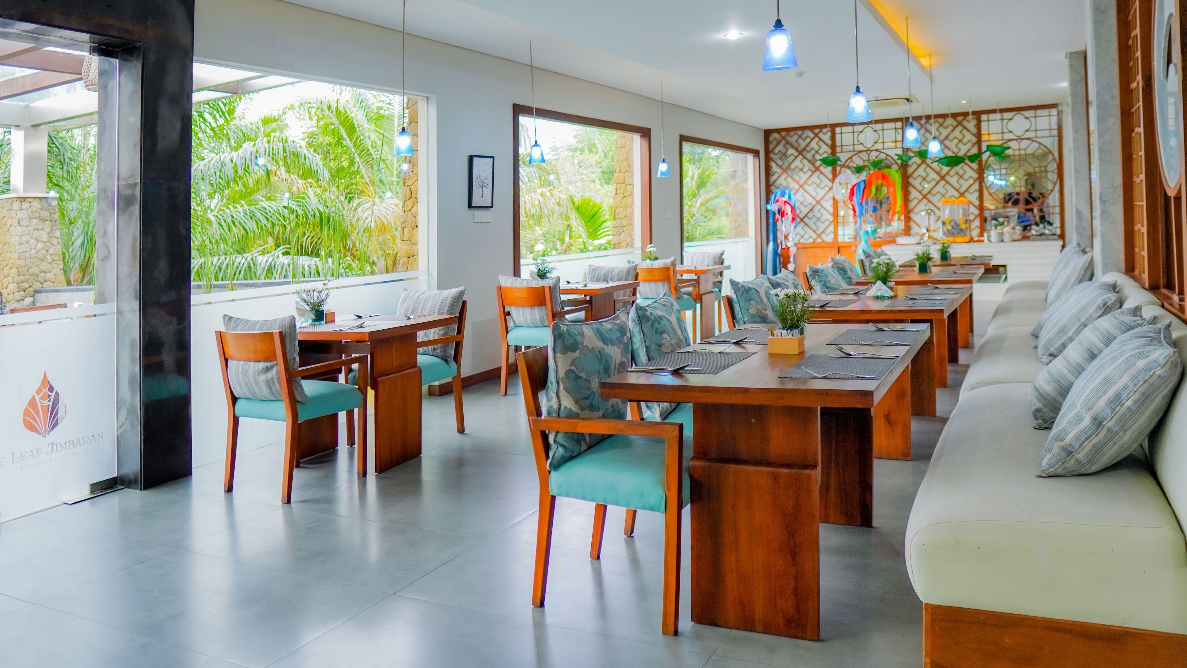 Un restaurant avec des tables et des chaises en bois, un long comptoir et un coin salon avec des canapés.