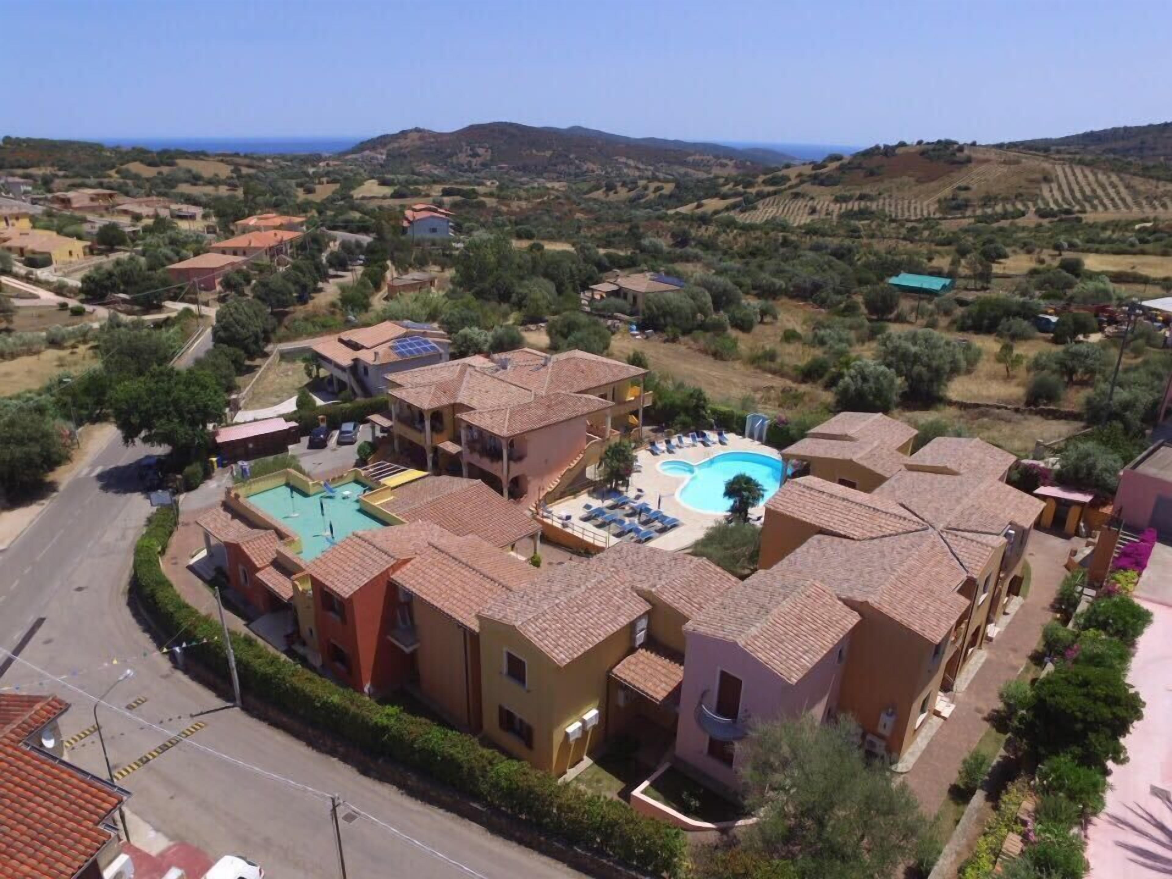 Un quartier résidentiel comprenant plusieurs maisons, une piscine et offrant une vue sur la mer.