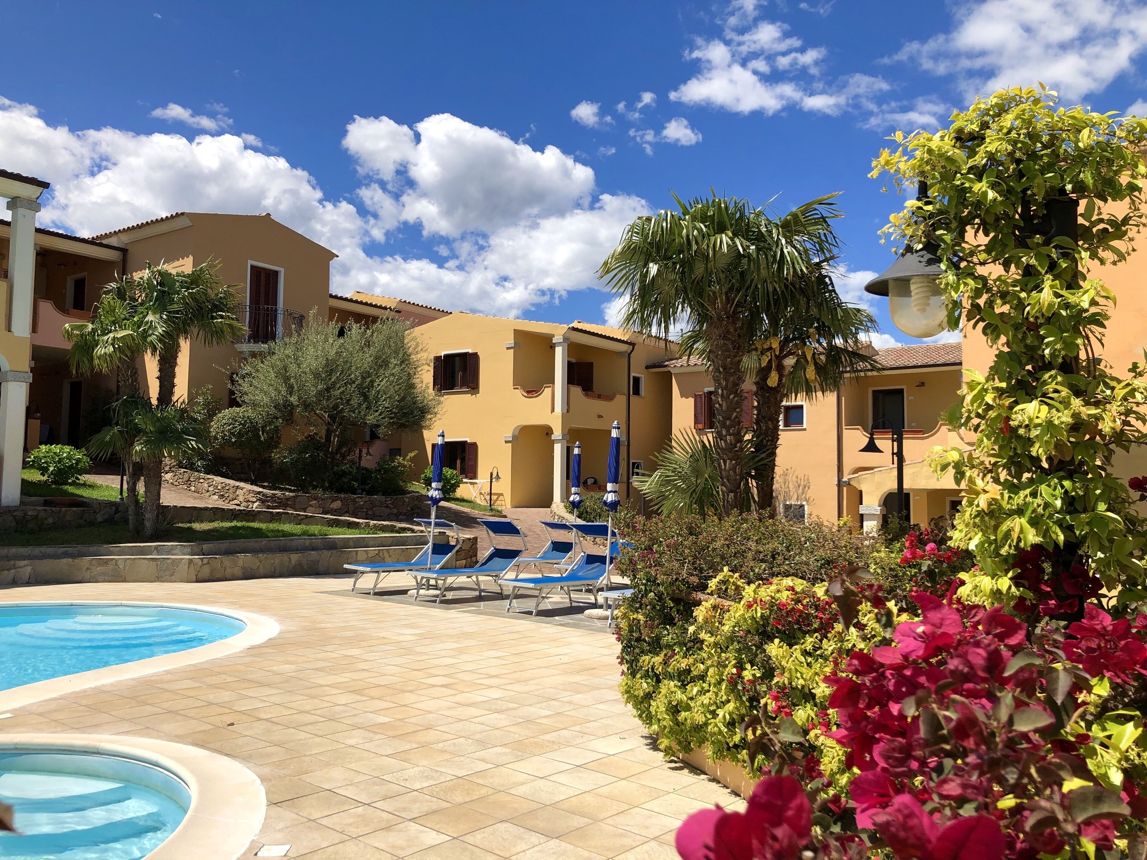 A pool area with lounge chairs and a clear blue sky.