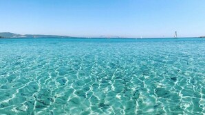 A clear view of a beach with shallow, turquoise water and distant sailboats. - Residence Corte dei Venti (Budoni)