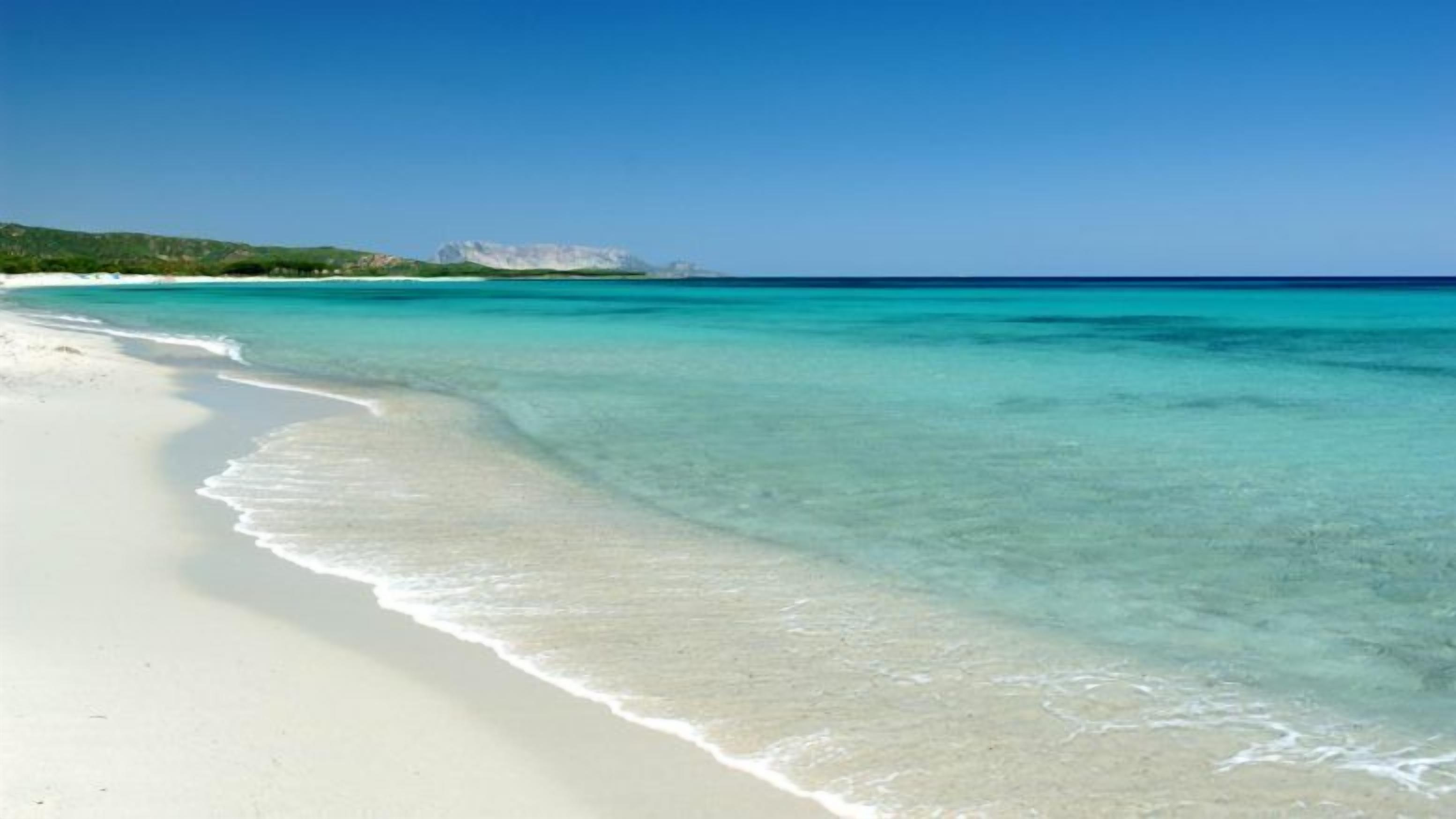 A beach with clear turquoise water and white sand.