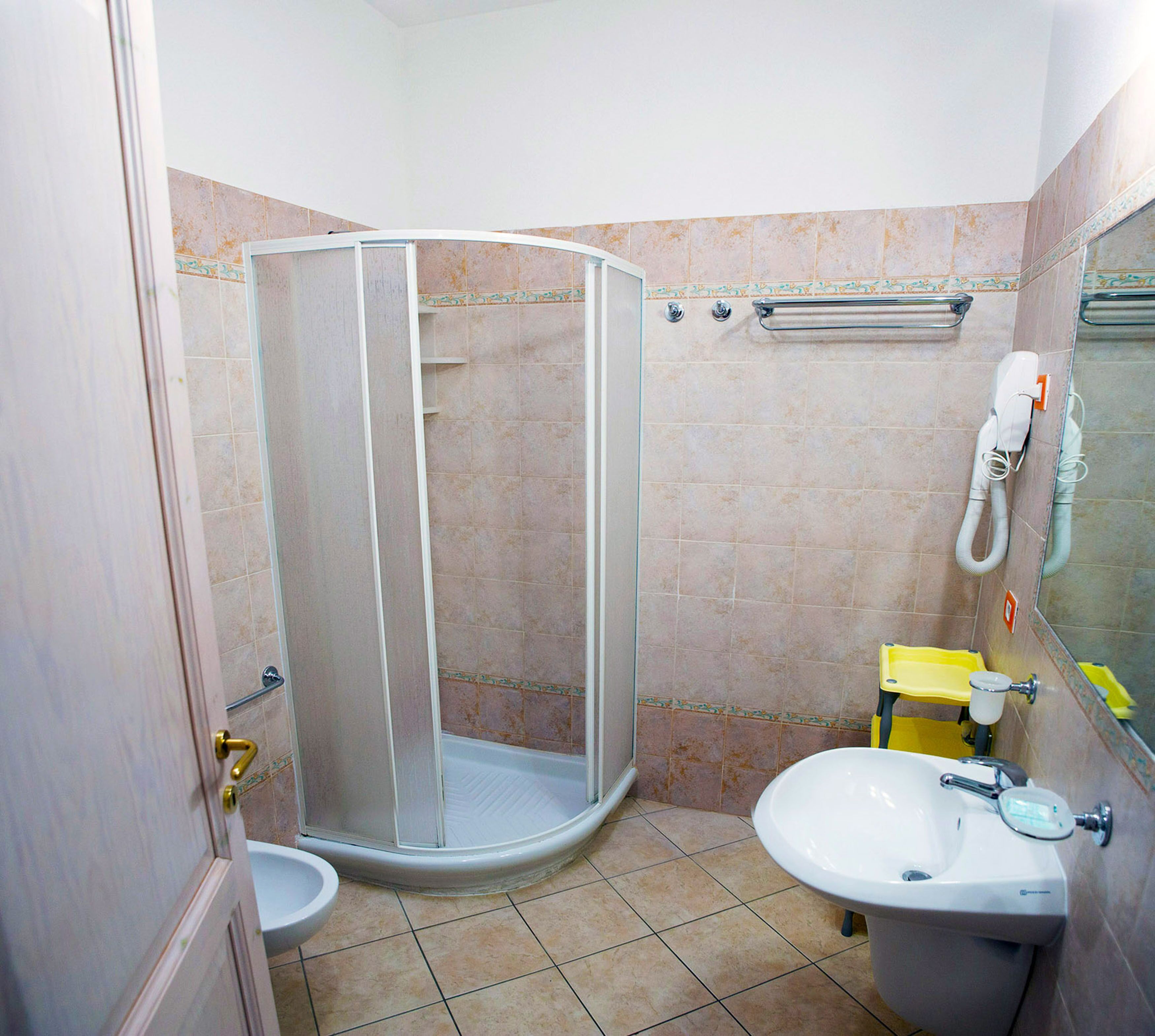 A bathroom with a shower enclosure, a sink, and a toilet.