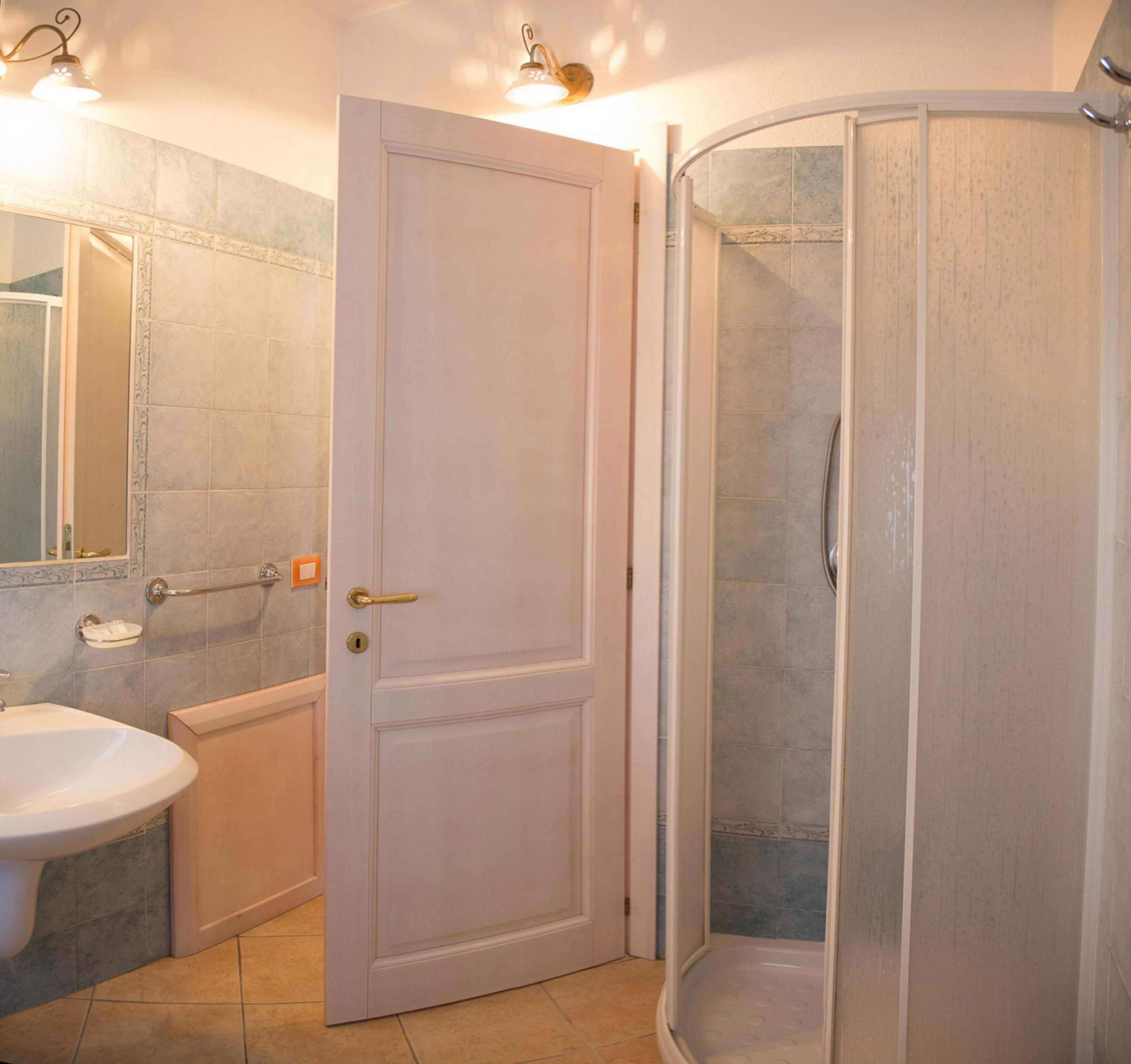 A bathroom with a white sink, a door, and a shower enclosure.