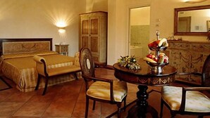 Habitación de hotel con una cama doble, un aparador de madera, una mesa redonda con frutero y un espejo en la pared.