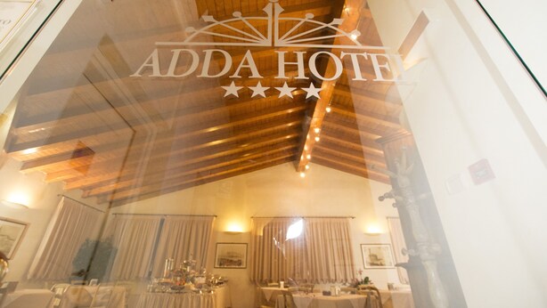 Interior de un hotel con comedor, techo de madera y un cartel que dice "ADDA HOTEL".