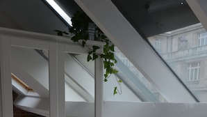 A bedroom with a white wardrobe, a wooden floor, a skylight, and a view of buildings outside. - AppartBrussels (Brussels)