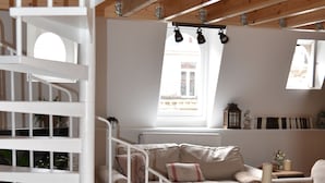 A modern interior with a white spiral staircase, a cozy seating area with a sofa and armchair, and a wooden ceiling. - AppartBrussels (Brussels)