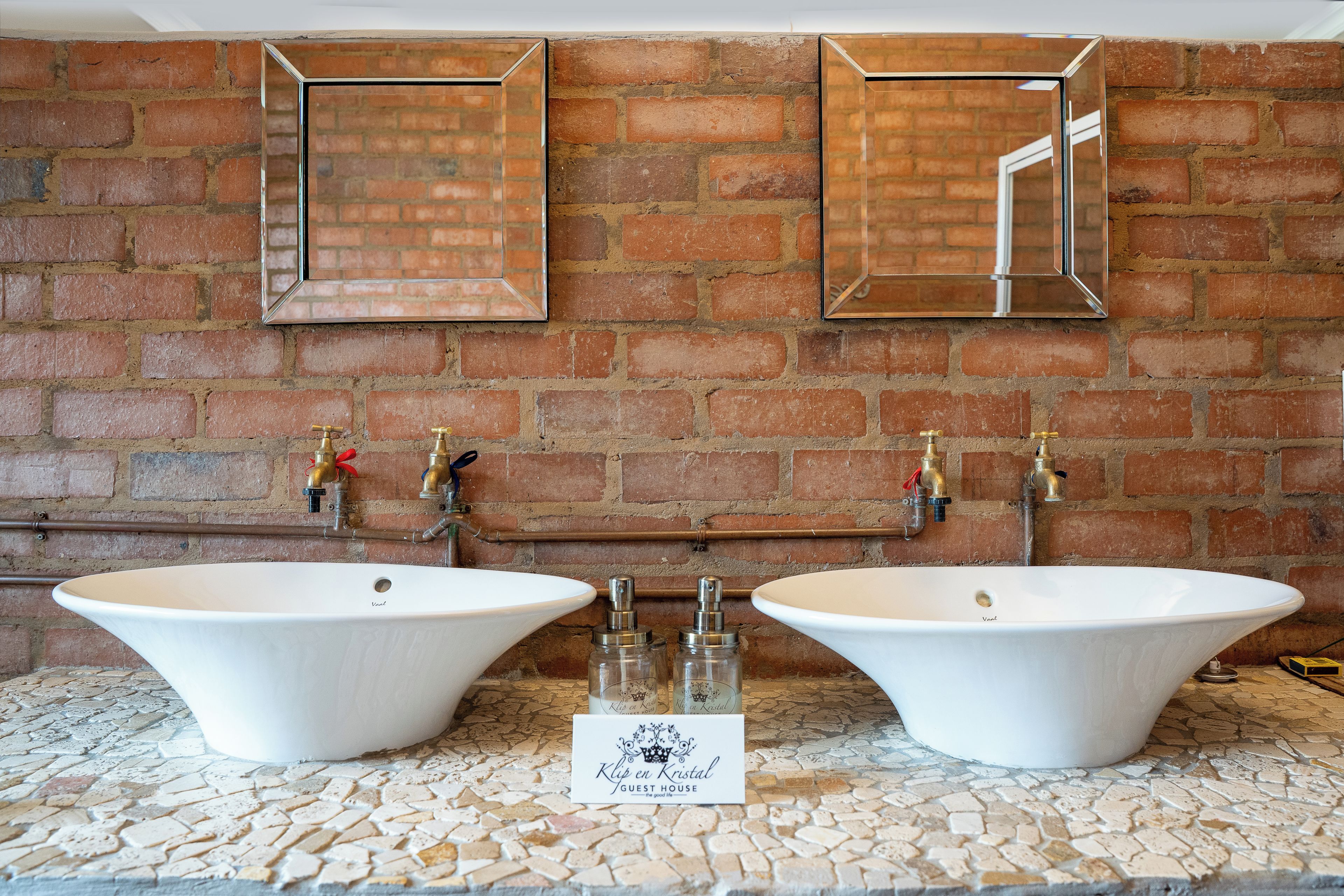 A bathroom with two large sinks, a mirror, and a sign indicating it's a guest house.