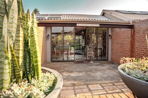 A reception area with a glass door, brick walls, and potted plants. - Klip en Kristal Guest House (Bela-Bela)