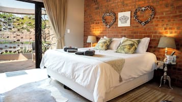 A bedroom with a large bed, a brick wall, two heart-shaped decorations, and a window with curtains.