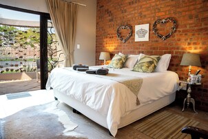 Un dormitorio con una cama grande, una pared de ladrillo, dos adornos con forma de corazón y una ventana con cortinas.