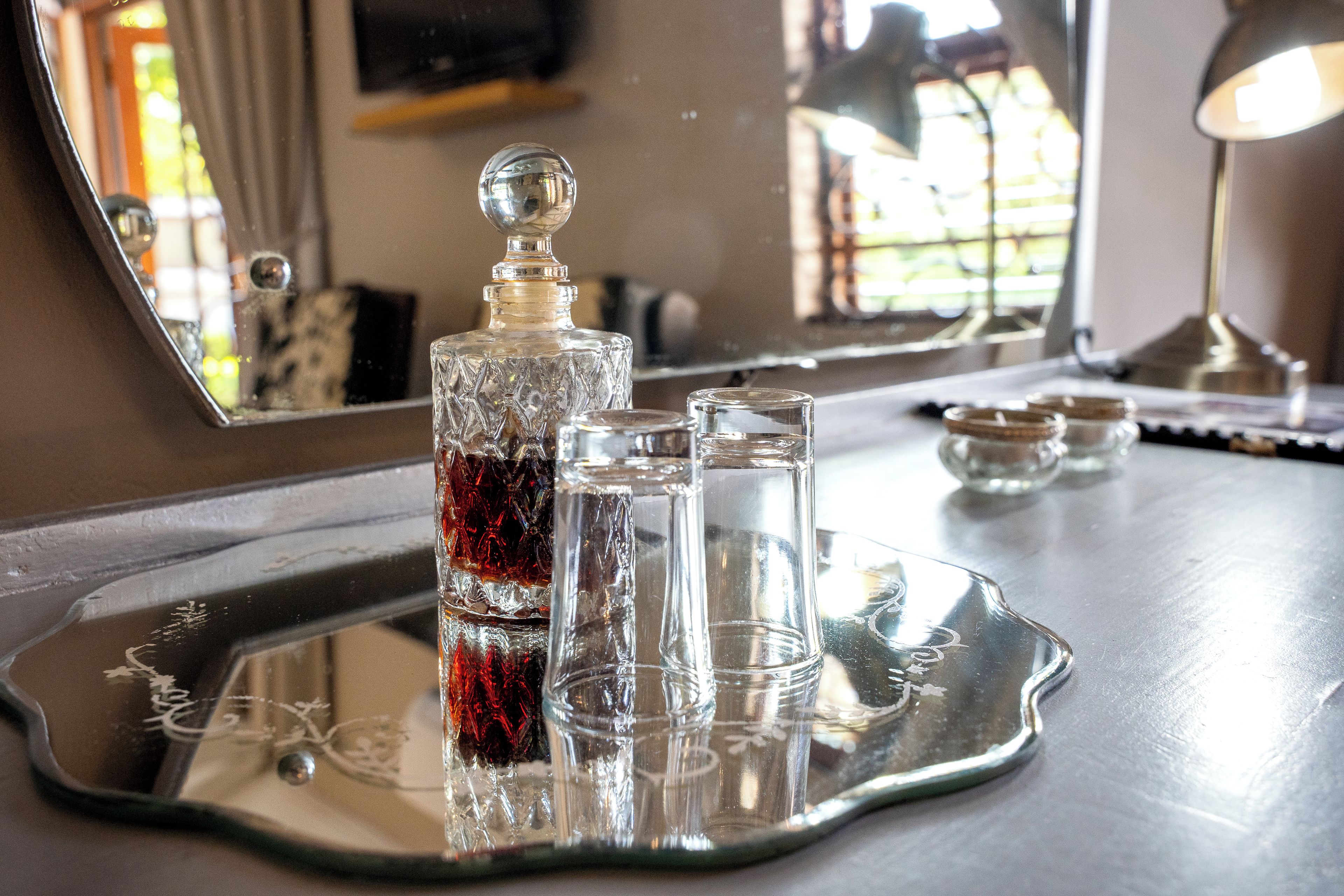 A tray with a decanter and glasses on a reflective surface.