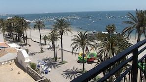 Strandblick mit Palmen, einem Steg und Booten.