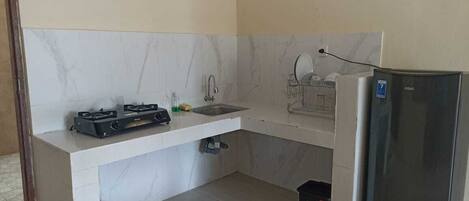 A compact kitchen with a gas stove, sink, and a refrigerator.