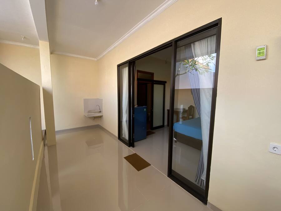 A hotel room with a sliding glass door leading to a balcony, a small sink, and a power outlet on the wall.