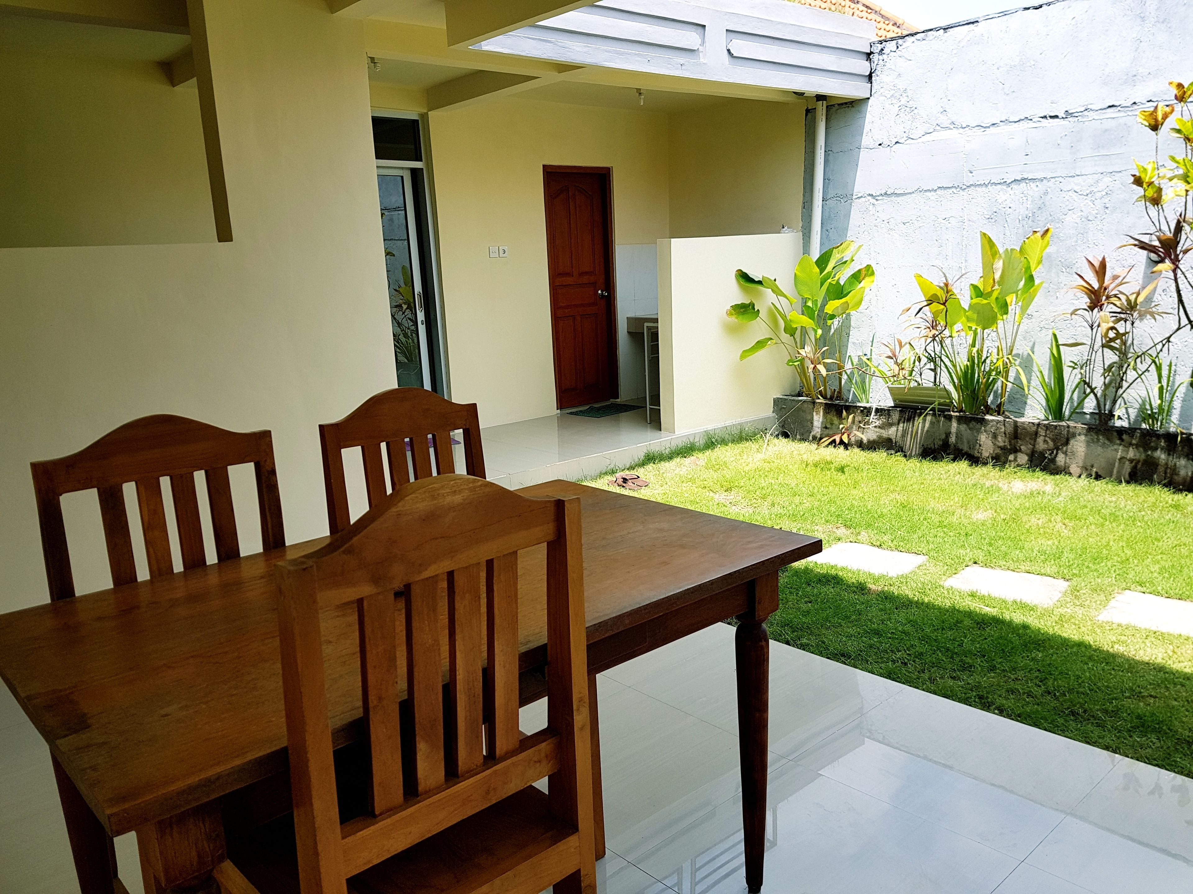A dining area with a wooden table and chairs, a small garden with plants, and a door leading to another room.