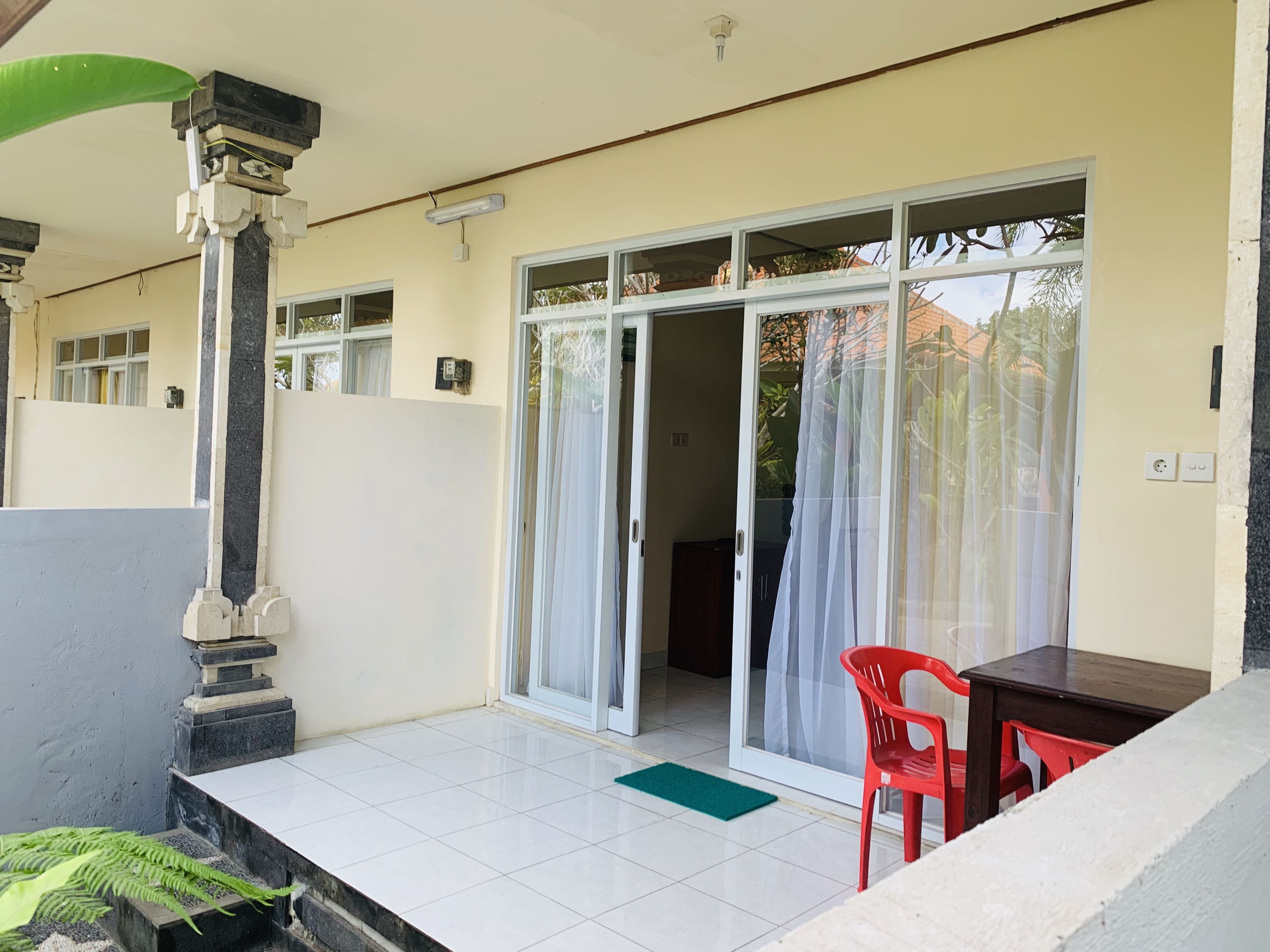 A room with a tiled floor, a sliding glass door, a red chair, and a small table.