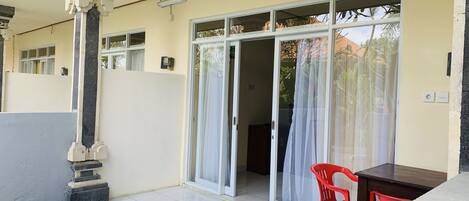 A room with a tiled floor, a sliding glass door, a red chair, and a small table.
