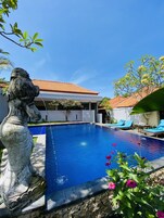 A swimming pool with a statue, a tiled roof, and a clear blue sky.