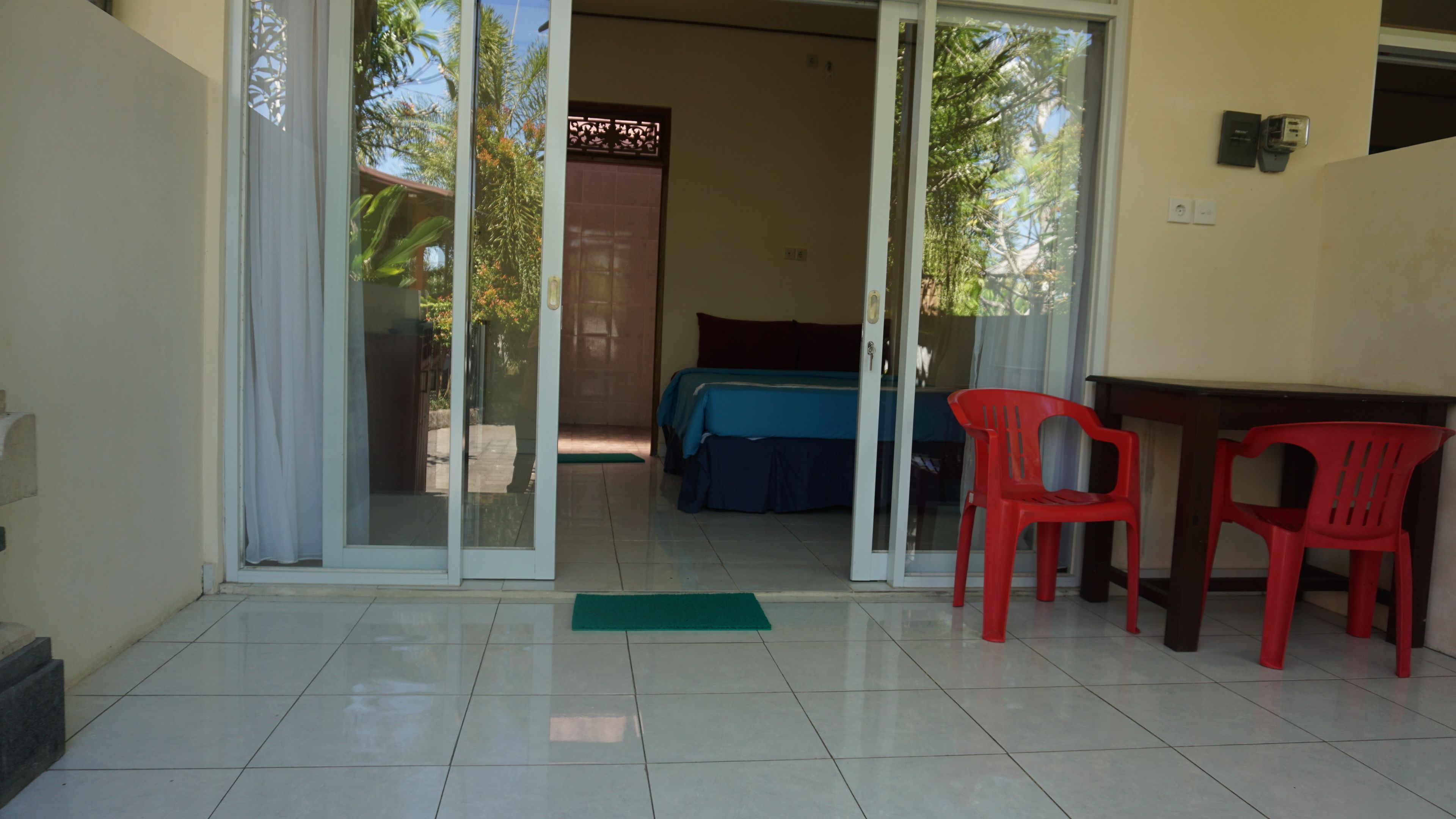 Quarto com uma cama, uma escrivaninha e duas cadeiras vermelhas.