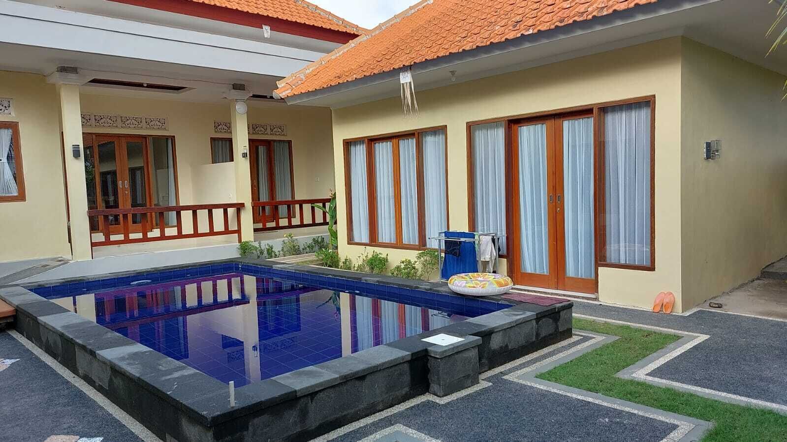 Un immeuble résidentiel doté d’une piscine, d’un patio couvert et d’un petit jardin.