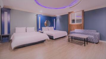 A hotel room with two beds, a sofa, a mirror, and a circular ceiling light.