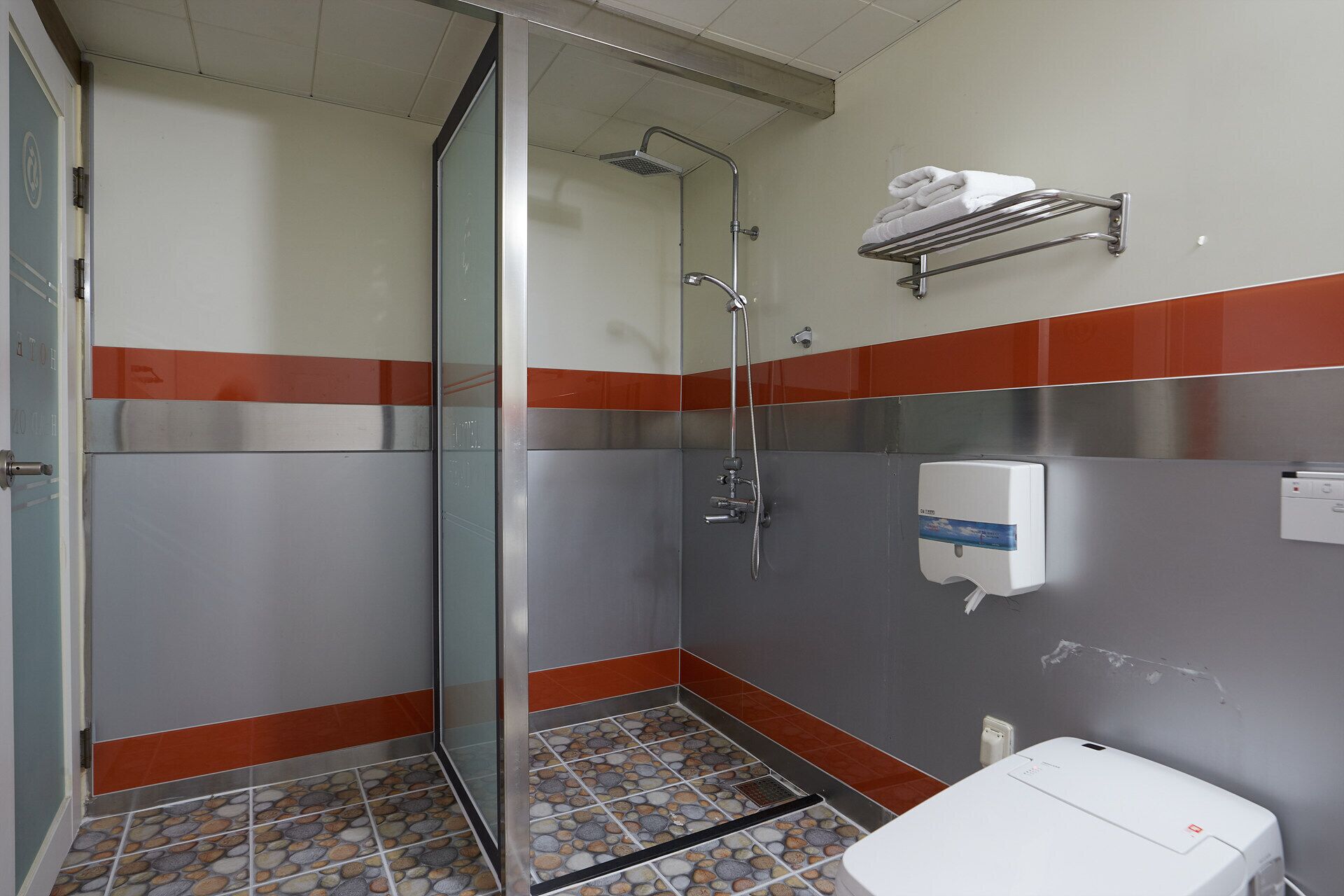 A bathroom with a shower, a toilet, and a towel rack.