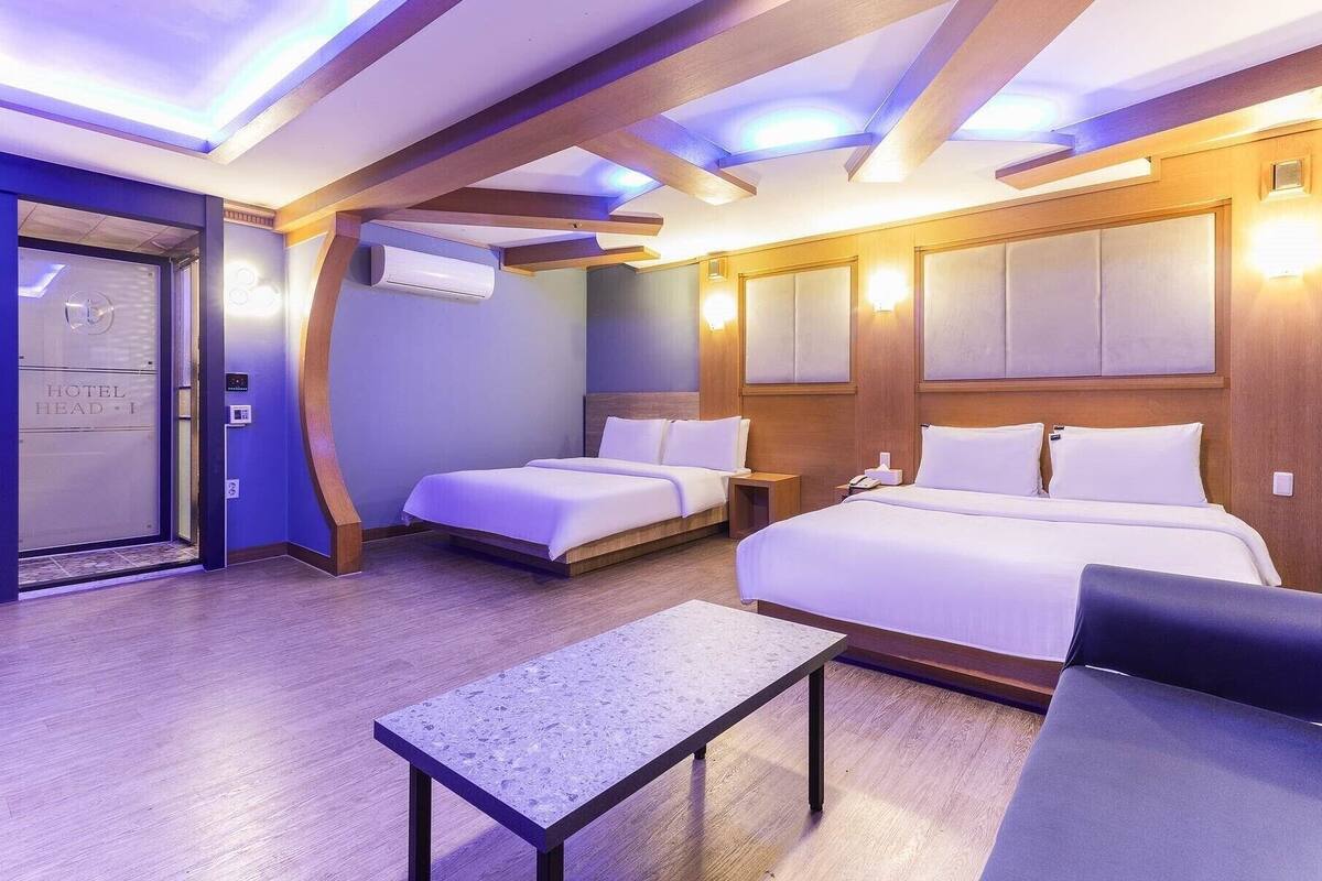 Una camera d'albergo con due letti, un tavolino e una struttura a volta in legno.