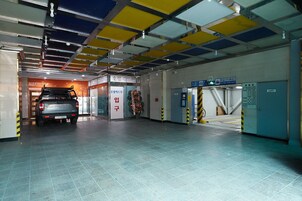 Una estación de metro con pisos de baldosas, un SUV estacionado y un ascensor azul.