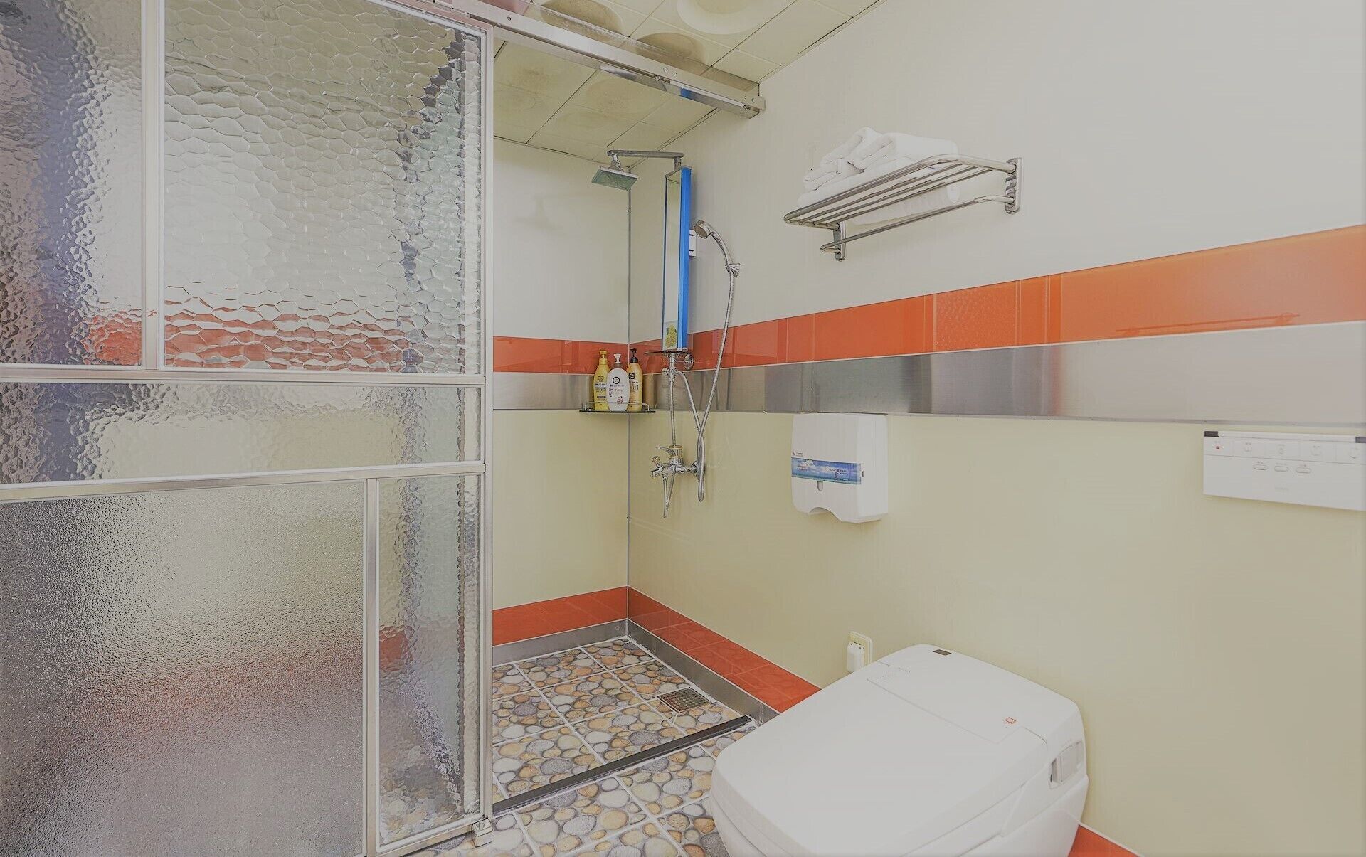 Une salle de bain avec une douche, des toilettes et un porte-serviettes.