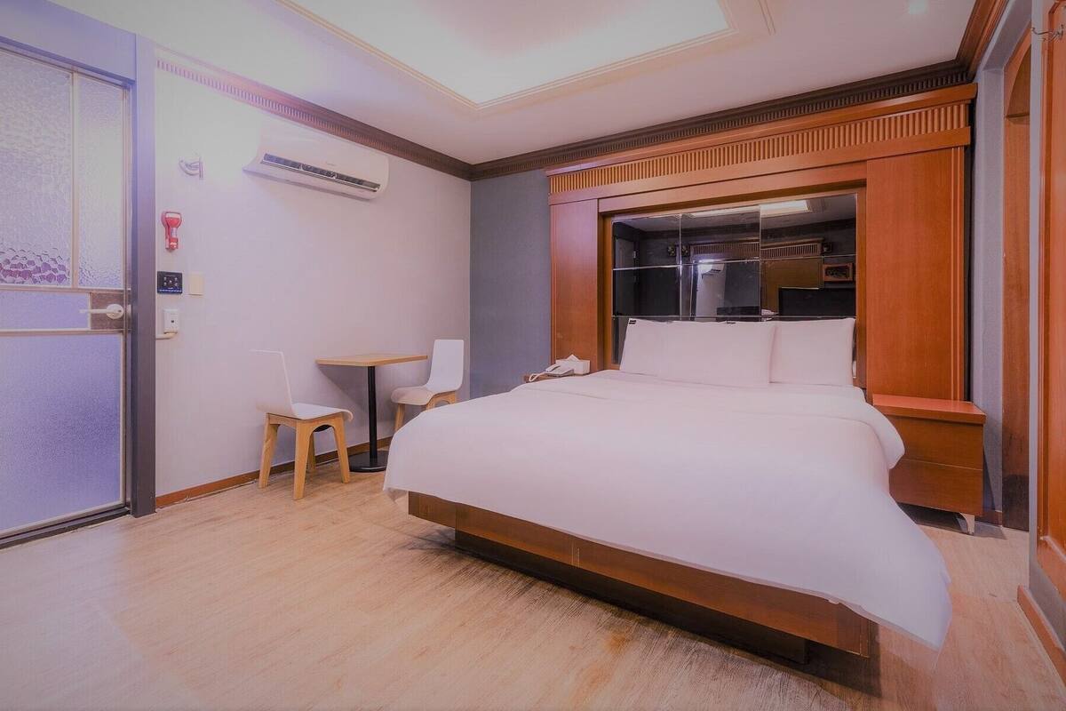 Camera d'albergo con un letto, una scrivania, una sedia, un condizionatore d'aria e un armadio.