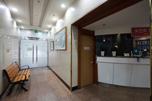 Un vestíbulo de hotel con una recepción, un banco de madera y una puerta que da a las habitaciones.