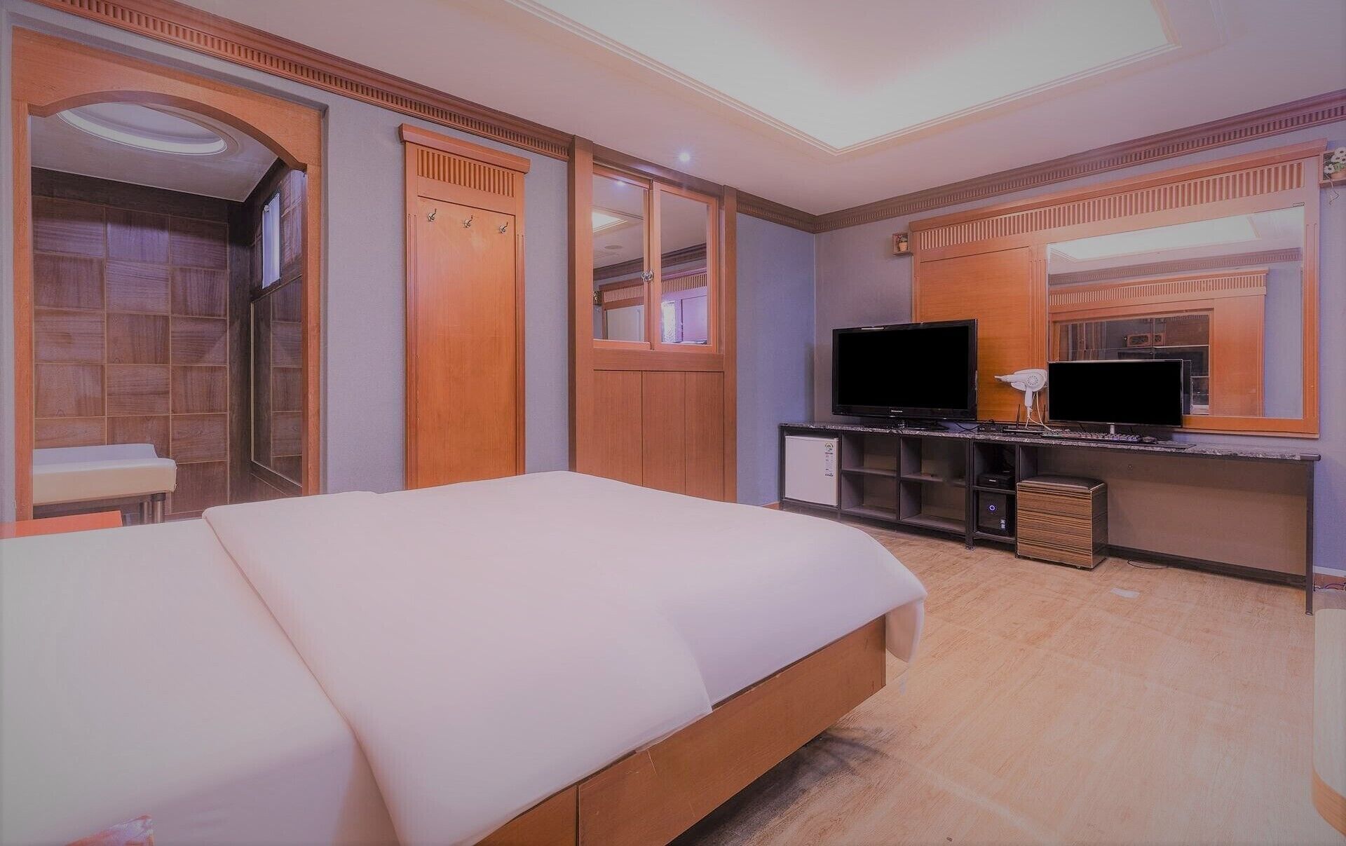 Une chambre d’hôtel avec un grand lit, une télévision, un miroir et une armoire.