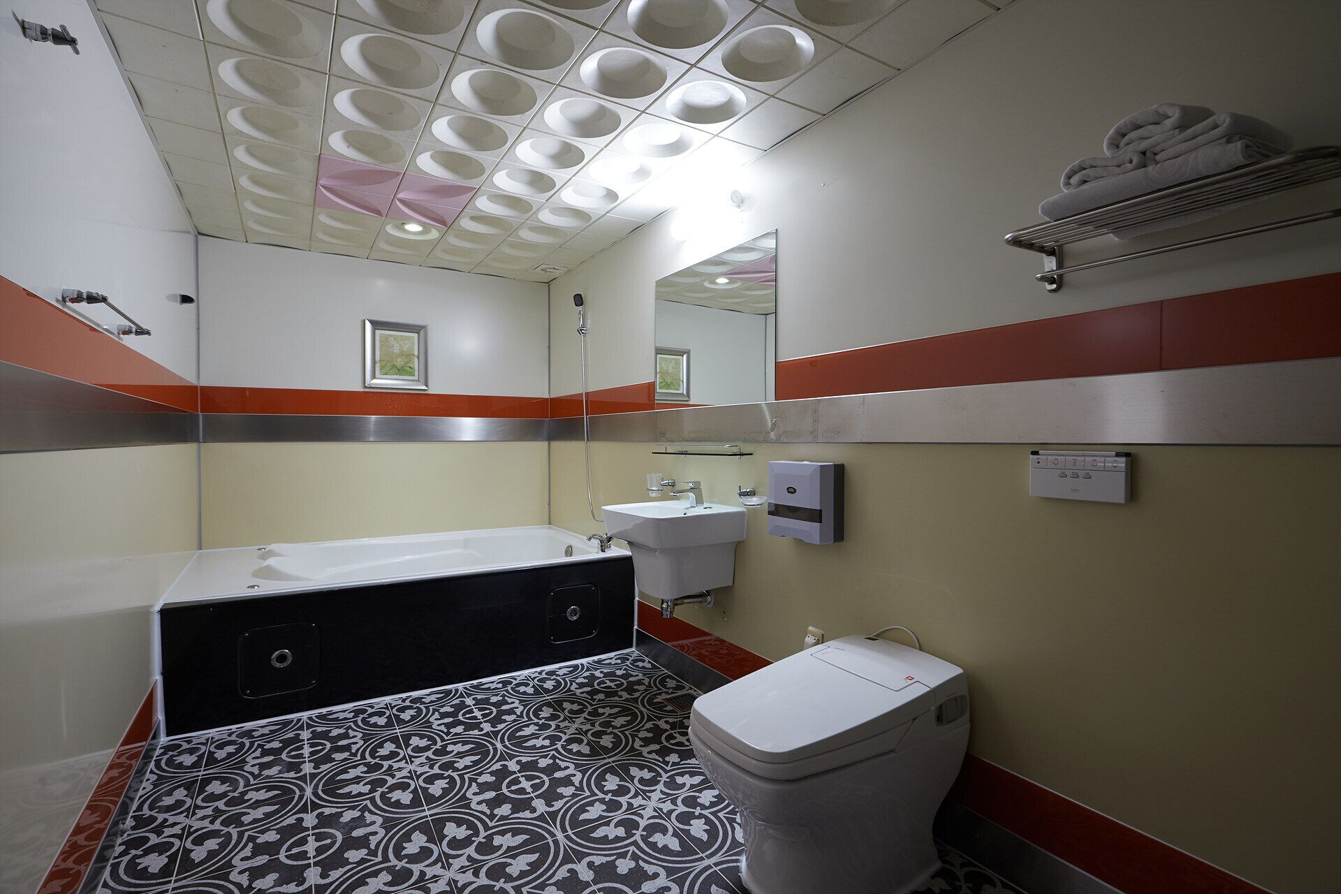 Un baño con bañera, inodoro, lavamanos y espejo.
