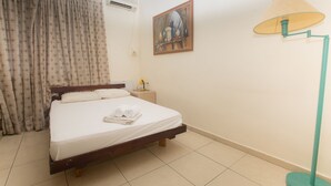 A neatly made bed with white linens and towels, a bedside table with a lamp, and a painting on the wall. - Ben Yehuda Hotel (Tel Aviv)
