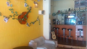 A bar area with stools, a counter with bottles, and a guitar on the wall. - Ben Yehuda Hotel (Tel Aviv)